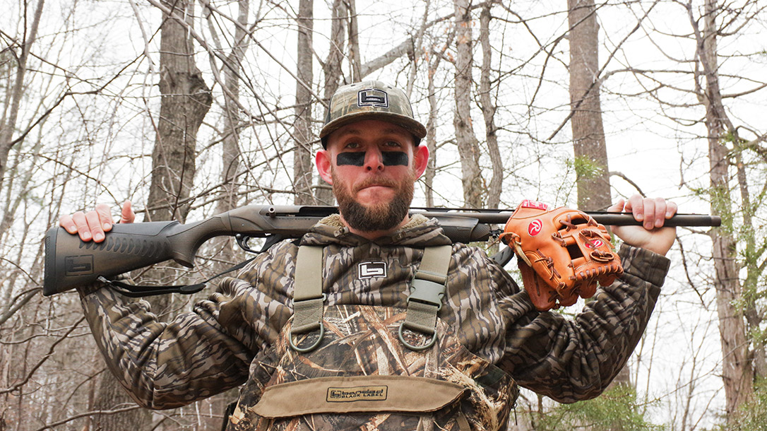 Brandon Snyder poses with two tools representing his dual trades, MLB and Hunting. A Benelli Super Black Eagle and Rawlings glove.