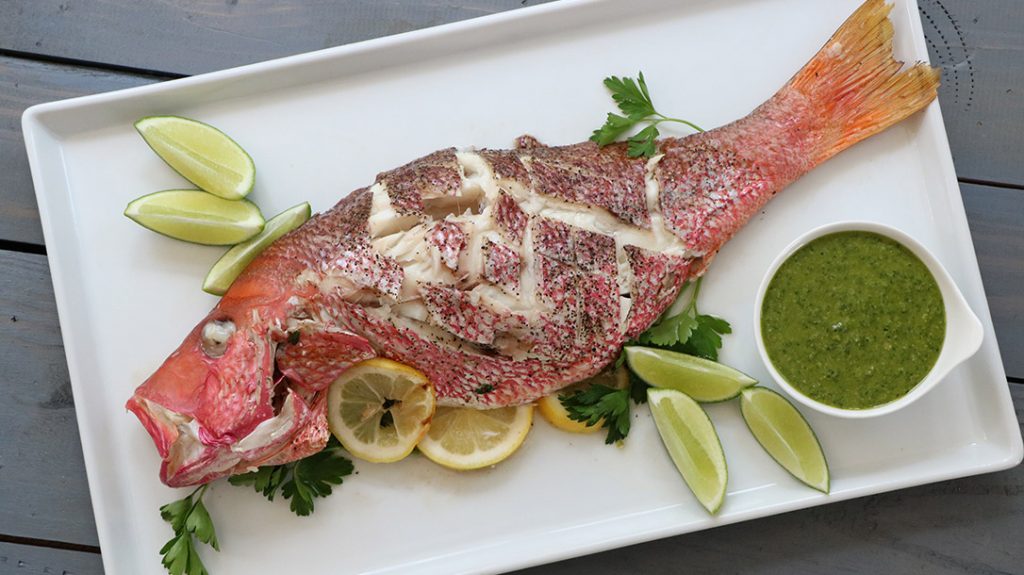 Pull the Snapper off the grill and place it on a plate with garnishes.